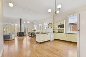 a large kitchen with white cabinets and a living room at Kilarra House - Heritage Home on Byng St Sleeps 10 in Orange