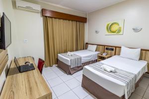 ein Hotelzimmer mit 2 Betten und einem TV in der Unterkunft Hotel Nacional Inn Araçatuba in Araçatuba