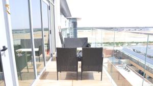 a balcony with two chairs and a view of an airport at Ivory Haven - Stylish 1BR Apartment in Oasis, Tranquil Stay Near Masdar Park in Abu Dhabi