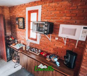 a kitchen with a brick wall with a microwave at Ecovalle São Thomé in São Thomé das Letras