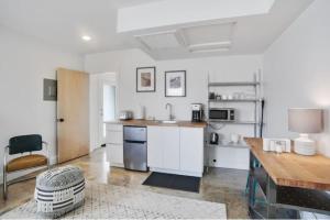 a kitchen with white cabinets and a sink and a table at River Breeze Quiet & Modern Black Pearl Apartment in New Orleans