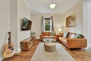 sala de estar con sofá y guitarra en Best Nest on March Cosy Home in CBD Firepit, en Orange