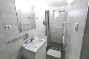 y baño blanco con lavabo y ducha. en Stardust apartman, en Pécs