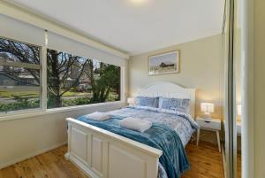 ein Schlafzimmer mit einem Bett und einem großen Fenster in der Unterkunft Collwood Cottage Cosy & Free Wifi in Orange