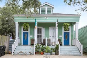 a green house with blue doors and flags on it at Art Filled Sanctuary in the Heart Of Mid City in New Orleans