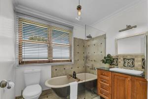 a bathroom with a tub and a toilet and a sink at Edwina Suite II - Fireplace, Elegant Heritage Home in Orange