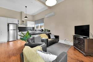 a living room with couches and a tv and a kitchen at Edwina Suite I - Sleek and Stylish CBD Wi-Fi in Orange