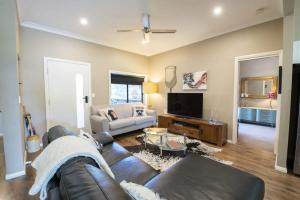 a living room with a leather couch and a television at Sterling House Spacious Deck BBQ Pet Friendly in Dubbo