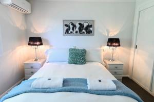 1 dormitorio con 1 cama blanca grande y 2 lámparas en Aspen Abode - CBD, Fireplace, BBQ, 3 Smart TVs en Dubbo