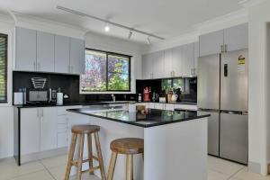 a kitchen with white cabinets and a island with bar stools at Narambla Estate - Rural Retreat, Luxe Hideaway in Orange