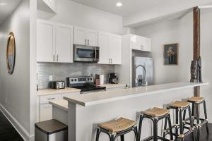 a kitchen with white cabinets and bar stools at Stylish 2-Bedroom Apartment in Garden District in New Orleans