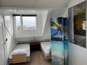 two beds in a small room with a window at Studio met eigen badkamer en eigen keuken in Nijmegen