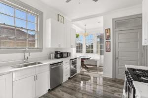 a white kitchen with white cabinets and a sink at Spacious Mid City 1BD On The Canal Streetcar Line in New Orleans +7 photos