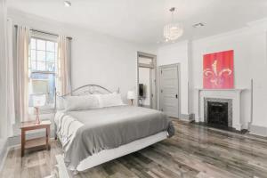 a white bedroom with a bed and a fireplace at Spacious Mid City 1BD On The Canal Streetcar Line in New Orleans