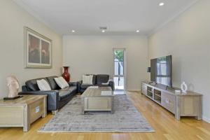 a living room with a couch and a tv at The Sampson Haven - Luxe CBD Getaway, Dog Friendly in Orange