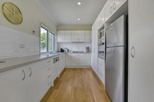 a kitchen with white cabinets and a refrigerator at The Sampson Haven - Luxe CBD Getaway, Dog Friendly in Orange
