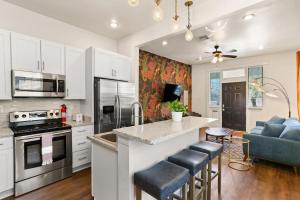 eine Küche mit weißen Schränken und eine Kücheninsel mit Barhockern in der Unterkunft Garden District 3BD 2BA Parking Stylish & Unique in New Orleans