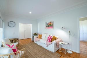 a living room with a white couch and a clock at Cobbora Cottage - Sleek & Stylish, Near Hospital in Dubbo