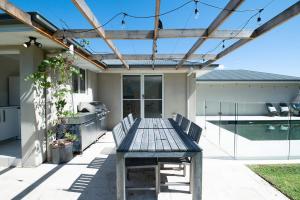 a patio with a wooden table and chairs at Regand Retreat - Pool, Luxurious Family Home in Dubbo