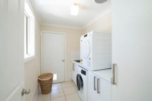 a white laundry room with a washer and dryer at Regand Retreat - Luxurious Family Home, Pool in Dubbo