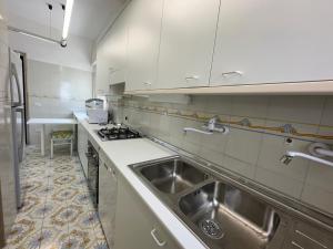 a kitchen with a stainless steel sink and white cabinets at Villa Paola by the sea in Cozze