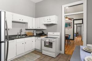 uma cozinha com armários brancos e um forno com placa de fogão em Gorgeous backyard Pool 2BD Midcity Retreat em Nova Orleans