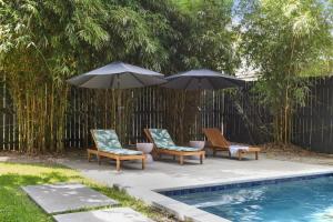 duas cadeiras e dois guarda-sóis ao lado de uma piscina em Gorgeous backyard Pool 2BD Midcity Retreat em Nova Orleans