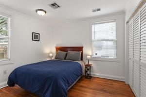 a bedroom with a bed with blue sheets and two windows at 4BD Metairie retreat with driveway and yard in Metairie