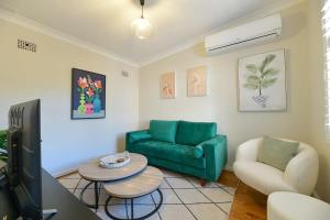 uma sala de estar com um sofá verde e uma mesa em Hope St Cottage II - Timeless & Serene Sanctuary em Bathurst