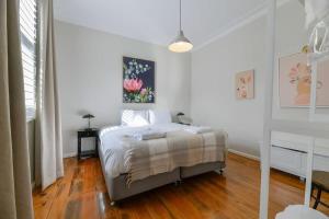 um quarto branco com uma cama e piso em madeira em Hope St Cottage II - Timeless & Serene Sanctuary em Bathurst