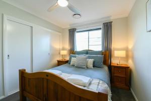 a bedroom with a bed with blue sheets and a window at Luxe on Lincoln - Close to Zoo, Rejuvenating Pool in Dubbo