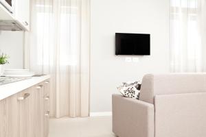 a white kitchen with a couch and a tv on a wall at Palazzo Talenti 1907 in Trieste