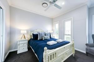 um quarto com uma cama com lençóis azuis e uma ventoinha de tecto em Serenity on Severn - Exquisite Family Home, 3 TVs em Dubbo