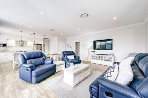 uma sala de estar com mobiliário azul e uma cozinha em Serenity on Severn - Exquisite Family Home, 3 TVs em Dubbo