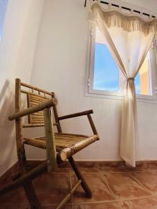 Una silla de madera en una habitación con ventana. en Montacala Holidays House, en Cumbre del Sol
