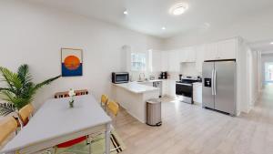 a white kitchen with a table and a refrigerator at Sunny 5Bed w Parking and direct Streetcar access in New Orleans