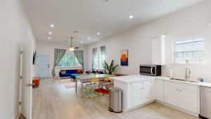 a kitchen with white cabinets and a living room at Sunny 5Bed w Parking and direct Streetcar access in New Orleans