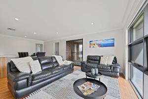 uma sala de estar com um sofá de couro e uma televisão em Bligh St Bliss - Ideal for Families, Mountain Views em Orange
