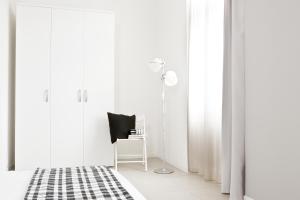 a white bedroom with a chair and a lamp at Palazzo Talenti 1907 in Trieste