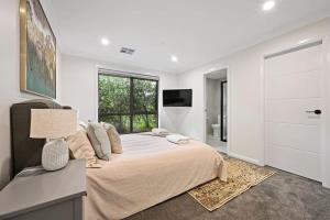 um quarto branco com uma cama grande e uma televisão em Bligh St Bliss - Ideal for Families, Mountain Views em Orange