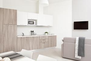 a white kitchen with a couch and a microwave at Palazzo Talenti 1907 in Trieste