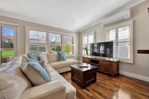 a living room with a couch and a flat screen tv at Heritage Charm on Hill - Tree-Lined Walk to Town in Orange