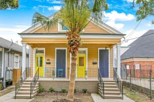 a yellow house with a palm tree in front of it at 5Bed StreetCar Retreat w Outdoor Entertaining in New Orleans