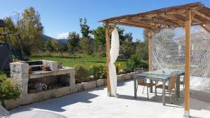 a patio with a table and a stone fireplace at Villa Piazzola in Petreto-Bicchisano