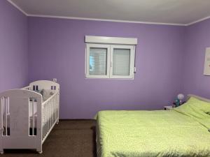 a purple bedroom with a bed and a window at Miris prirode in Vrdnik