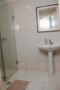 a white bathroom with a sink and a shower at Studio 110 in Luanda
