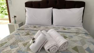 a bed with white towels and pillows on it at Chalés Família Onofre in Divisa