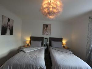 two beds in a room with a chandelier at Cribyn Lodge in Brecon
