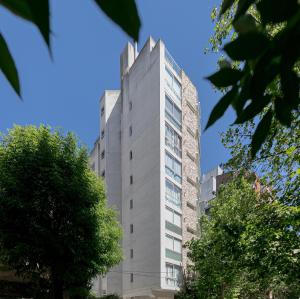 un alto edificio gris con árboles delante de él en Jion en Mar del Plata