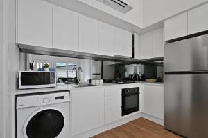 a white kitchen with a microwave and a dishwasher at The Elm Apartments - The Orange Room in Orange